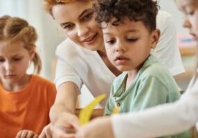 Smiling,Teacher,Talking,To,African,American,Kid,Near,Children,In